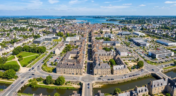 Vue aérienne ou paysagère de la ville de Vannes avec ses quartiers résidentiels et commerciaux, montrant le tissu urbain et les environs, en journée avec une bonne luminosité naturelle. L'image doit transmettre l'accessibilité et la proximité de l'entreprise pour les habitants de cette zone géographique. Aucun texte, logo ou filigrane ne doit être visible.