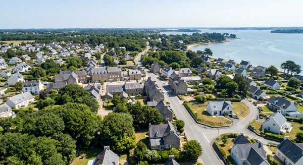 Vue aérienne ou paysagère de la commune d'Arradon en Bretagne sud, photographiée en journée avec une bonne luminosité naturelle. L'image doit montrer le tissu urbain, les quartiers résidentiels, les routes d'accès et les alentours caractéristiques de la région. Elle doit transmettre l'accessibilité et la proximité d'Arradon comme zone d'intervention de l'entreprise. Photographie réaliste de haute qualité professionnelle sans texte, logo ou filigrane visible.